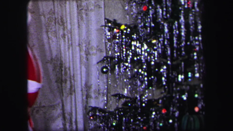 1971 Lynbrook home-movie frame with part of a Santa costume at the edge of a living room Christmas tree scene.