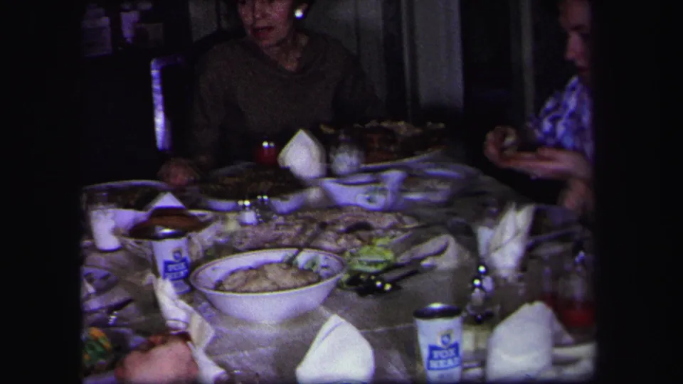 1971 Lynbrook home interior showing a family dinner table with dishes, glasses, folded napkins, seated adults, and a Fox Beer can.