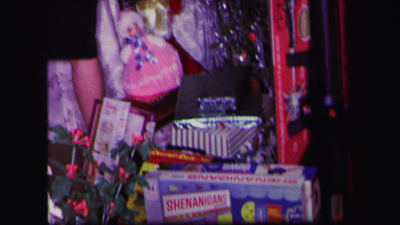 1971 Lynbrook home-movie frame with a pink doll, boxed games, holly, tinsel, and a red Sonic Blaster toy beside the gift display.