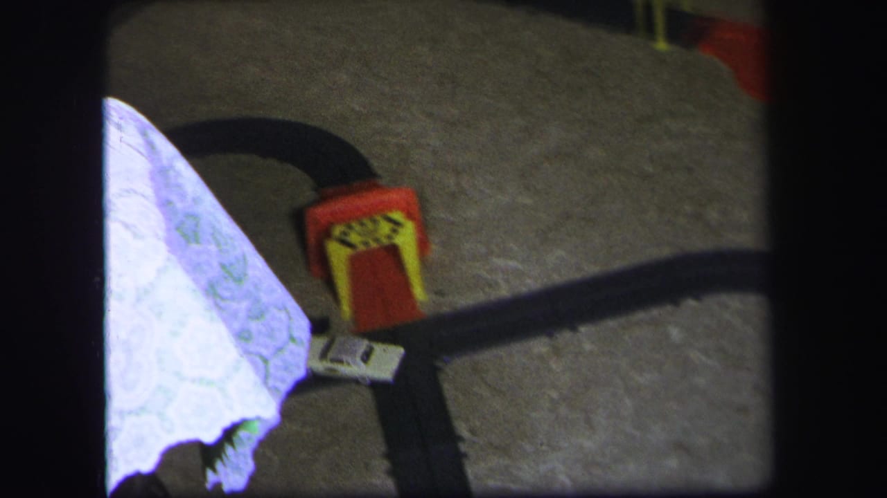 Close view of a tabletop or floor area with a bright paper or cake piece and red decoration nearby.