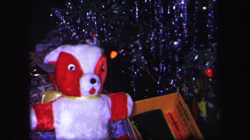 1971 Lynbrook 8mm frame showing a closer view of the plush dog, wrapped gifts, and reflective tinsel under the tree.