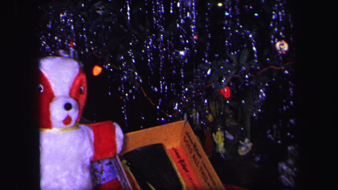 Christmas tree tinsel, red lights, stuffed dog toy, and boxed toy BB gun under the tree.