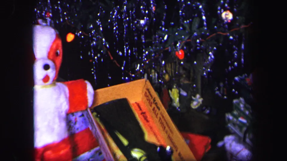 The camera has moved closer to the toy BB gun box and stuffed dog under the Lynbrook Christmas tree, with dark 8mm shadows around the frame.
