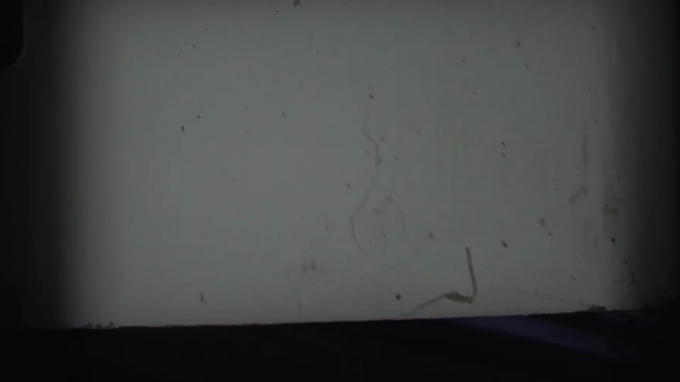 Opening 1971 8mm frame from a moving car, mostly dark border and window obstruction before the roadside sign becomes clear.