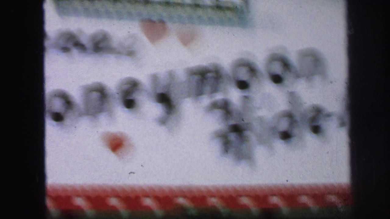 Soft 1971 Lynbrook 8mm frame showing a white handmade welcome sign with red heart trim and blurred black lettering.