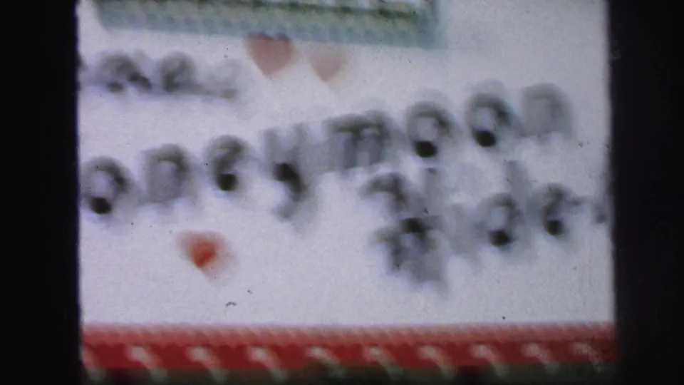 Soft 1971 Lynbrook 8mm frame showing a white handmade welcome sign with red heart trim and blurred black lettering.