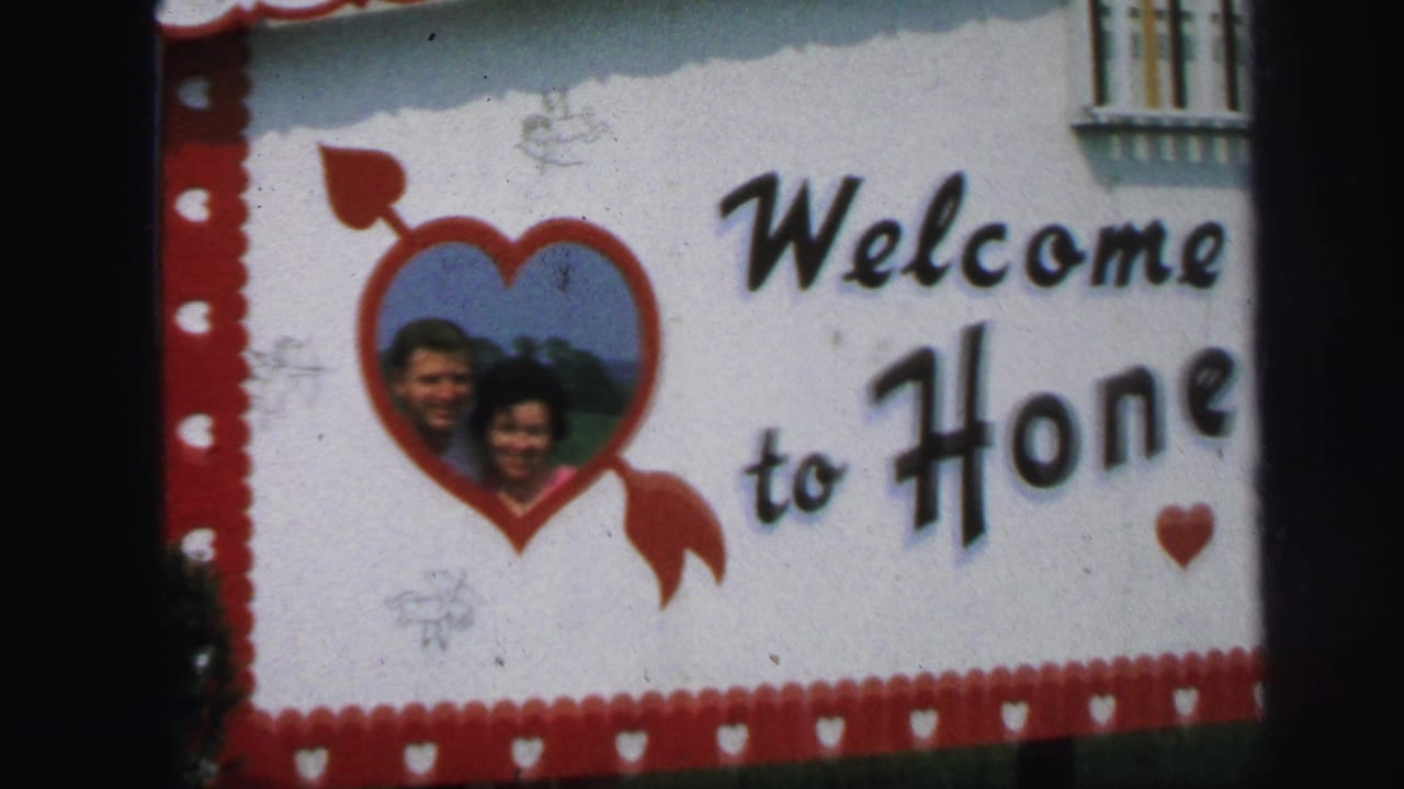 Welcome sign with heart-framed couple portrait and black lettering.