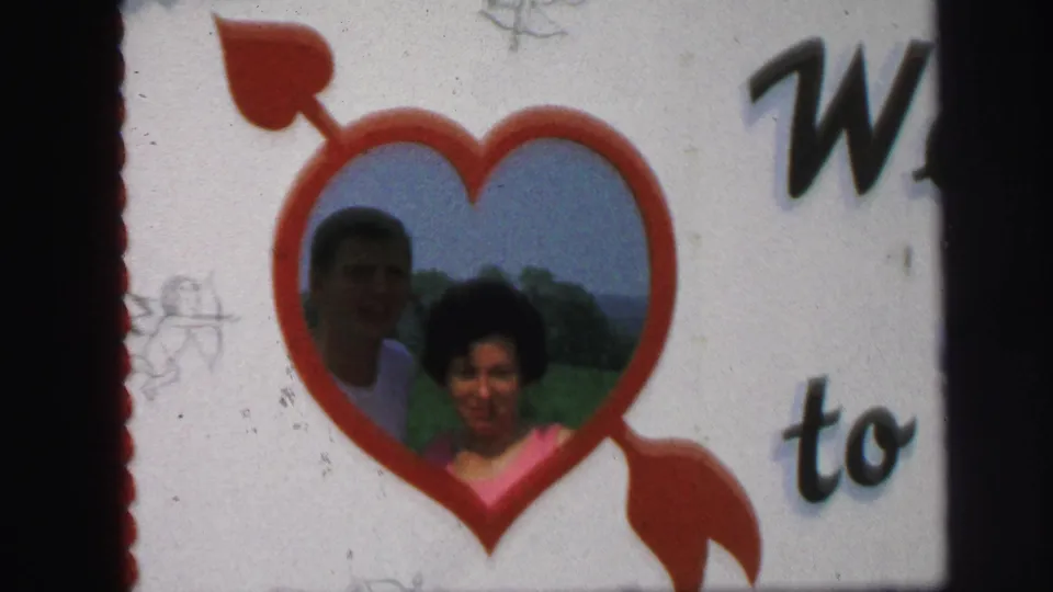 The final frame shows the couple farther back in the red heart cutout, with handwritten-style text and white sign space around them.