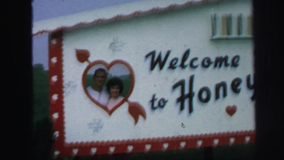A wider handheld frame shows the couple's heart portrait beside painted welcome lettering and a red filmstrip-style border.