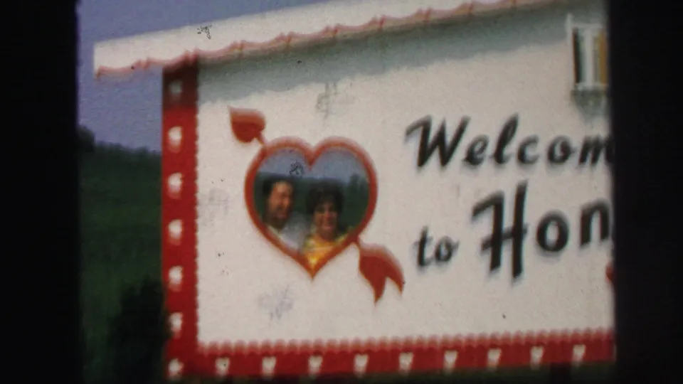 A wider 1971 Lynbrook view shows the decorative sign with the couple in a heart frame and partial words reading welcome to Hon.