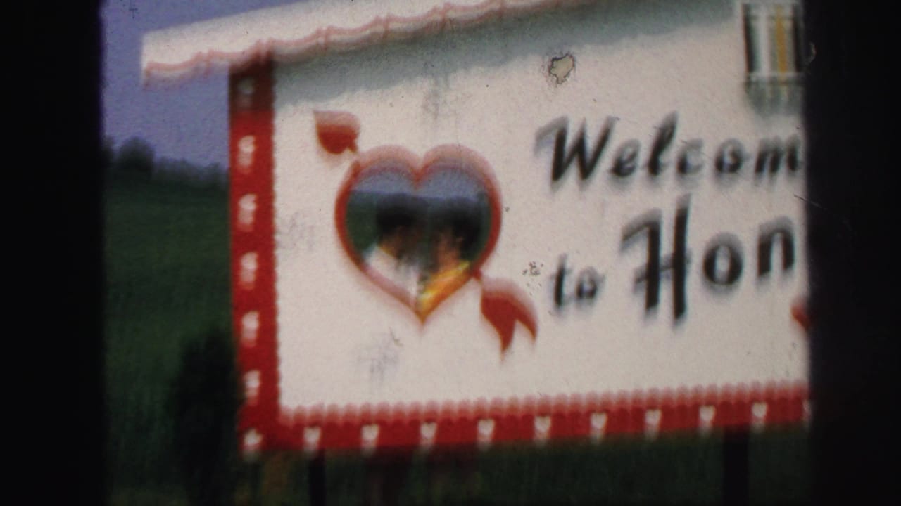 1971 Lynbrook frame with a white and red welcome sign, partial lettering, and a heart-shaped opening reflecting people or scenery.