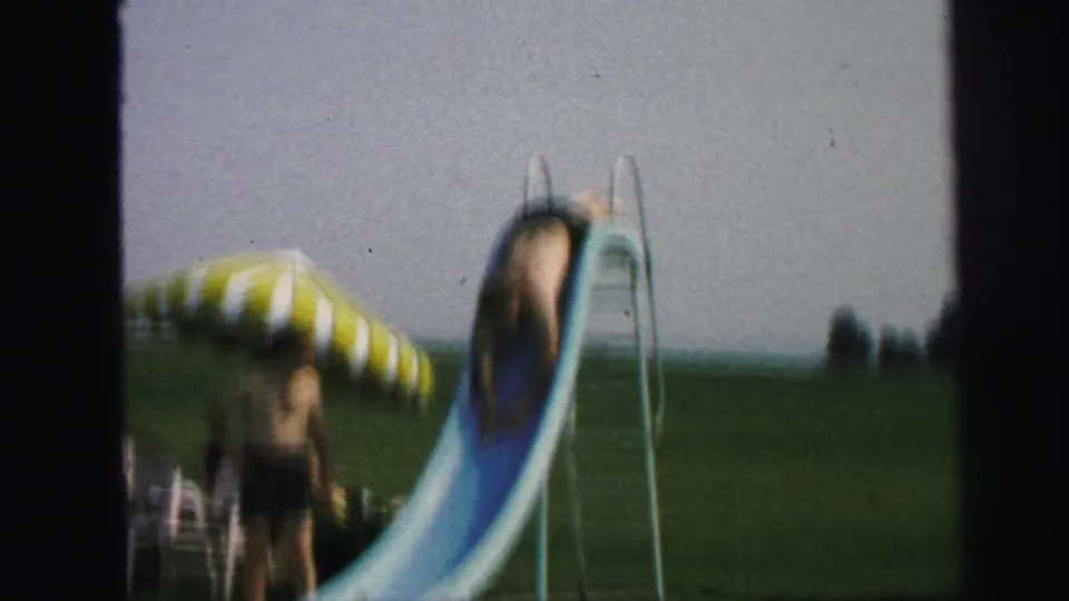 In the Lynbrook 1971 poolside scene, a child descends a blue slide with a striped umbrella and lawn behind.