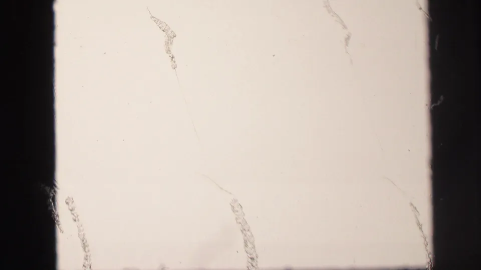 Mostly blank overexposed 8mm frame from the Lynbrook pool clip, showing scratches, dust marks, and dark gate edges.