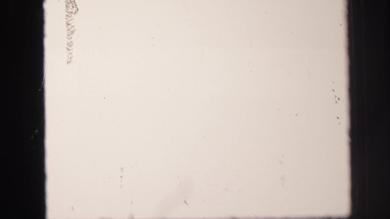 Overexposed opening frame from the 1971 Lynbrook 8mm clip, with film gate edges and faint marks visible.
