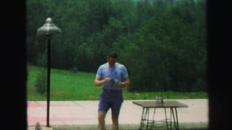 In the 1971 Lynbrook yard scene, the man looks down near the small billiards table with a lamppost and dense trees behind him.