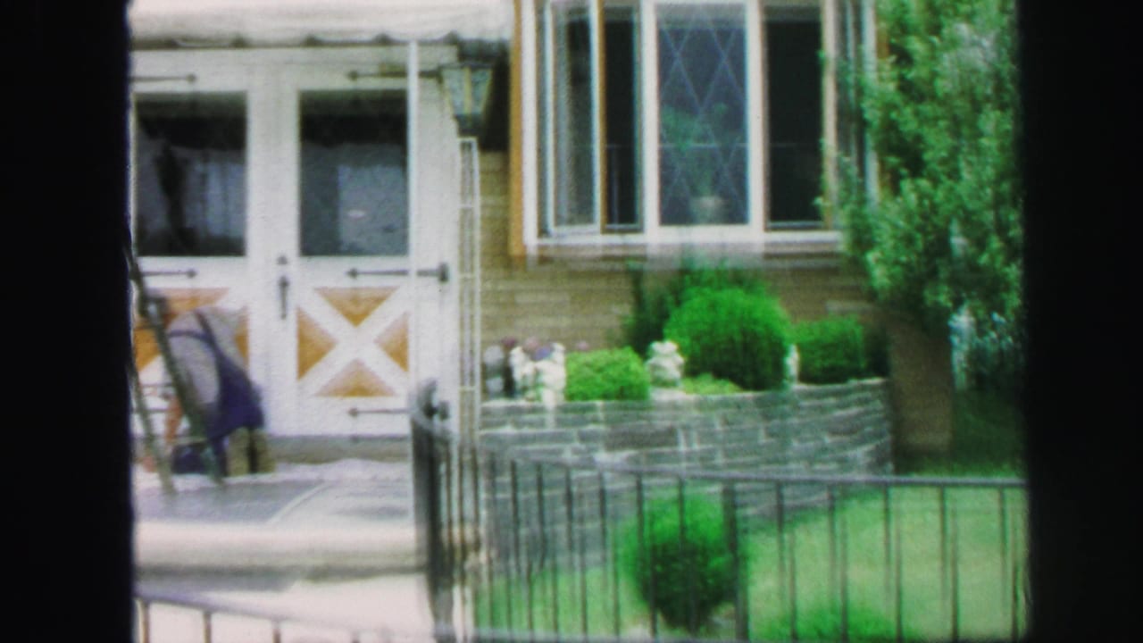 Front entrance with white double doors, shrubs, lawn, fence, and a person near a ladder.