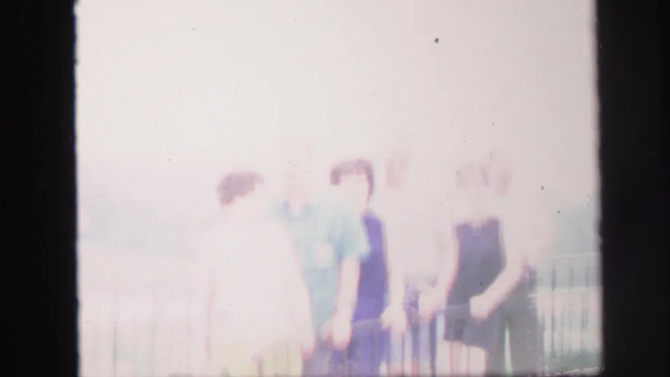 Final overexposed frame of adults near a railing in the 1971 Lynbrook home-movie clip.