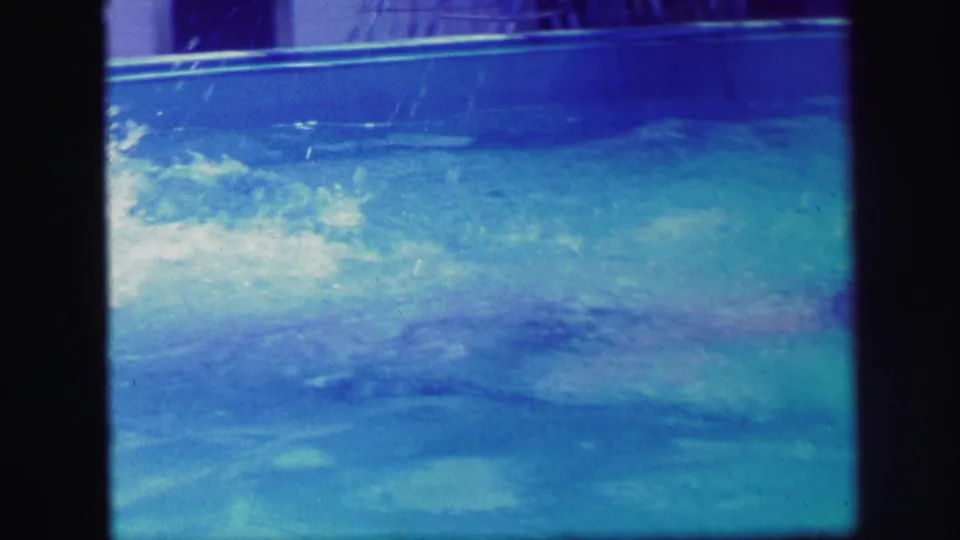 1971 Lynbrook pool footage shows a swimmer beneath the surface as ripples and splash residue move across the water.