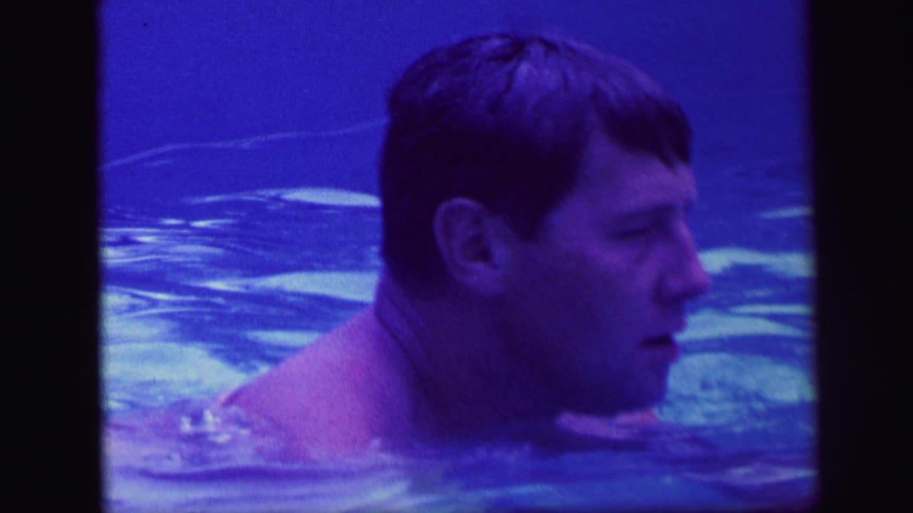 Adult swimmer in profile with his head above rippling blue water.