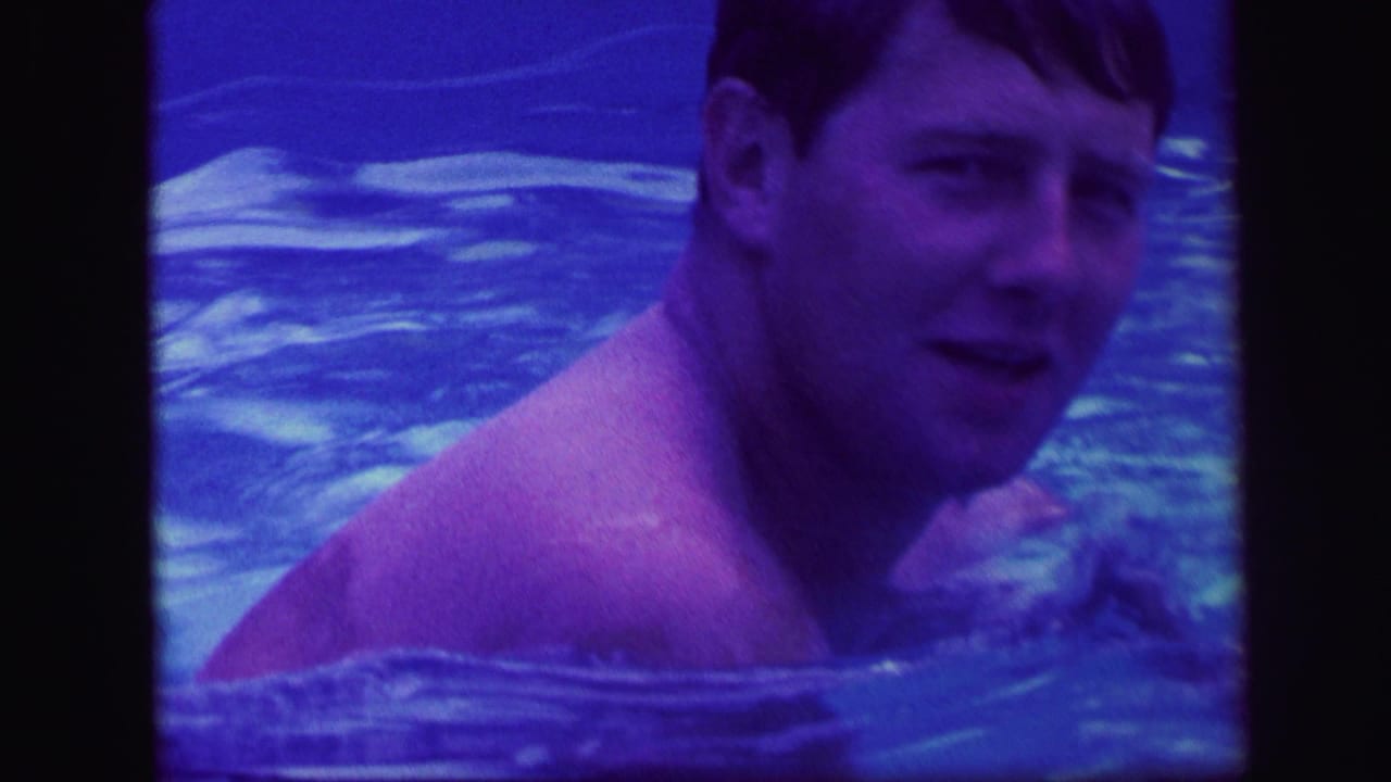 A man in a swimming pool turns toward the camera in a blue-tinted 1971 Lynbrook home-movie frame.