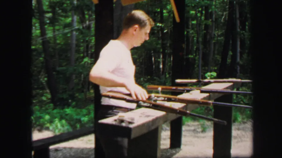 At the wooded Lynbrook range, the man turns to the side as rifles rest across the wooden station in the final frame.