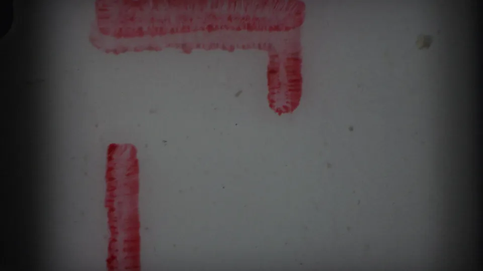 1971 Lynbrook 8mm reel-end frame showing a partial red L-shaped marker, pale film surface, dust specks, grain, and dark gate borders.