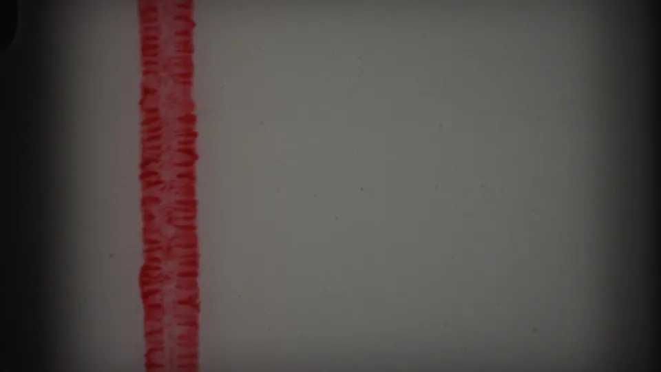 1971 8mm Lynbrook reel frame showing blank film area with a vertical red marking, grain, dust, and dark gate-edge shadows.