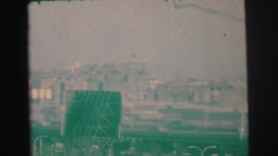 End of the 1973 Lynbrook pan looking toward rooftops and distant structures, with a large dark sign-like form in the foreground.