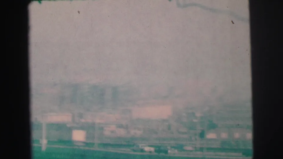 1973 Lynbrook, New York 8mm frame showing a soft, hazy view over roads, rooftops, and industrial-looking structures.
