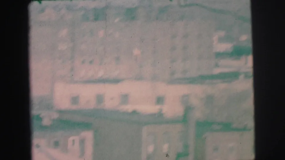 1973 Lynbrook, New York home-movie frame showing a hazy, soft-focus cluster of low buildings and rooftops.