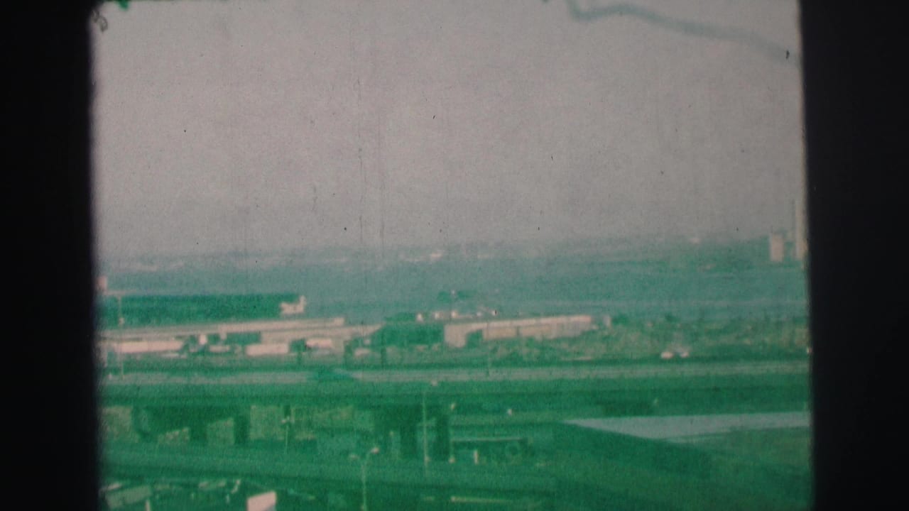 Similar elevated view of overpasses and low buildings across a hazy urban landscape.