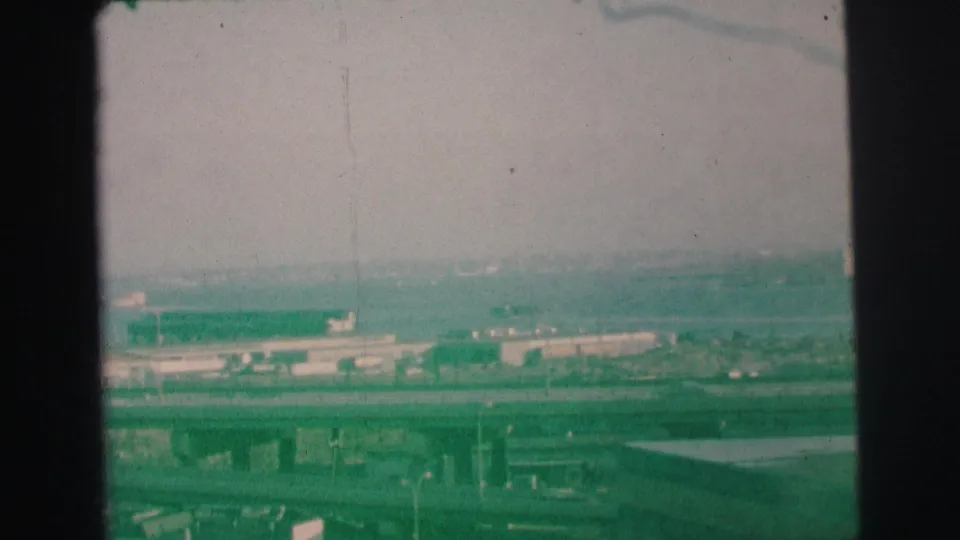 1973 Lynbrook, New York 8mm frame showing bridges, road corridors, low industrial structures, and a pale water or marshy area.
