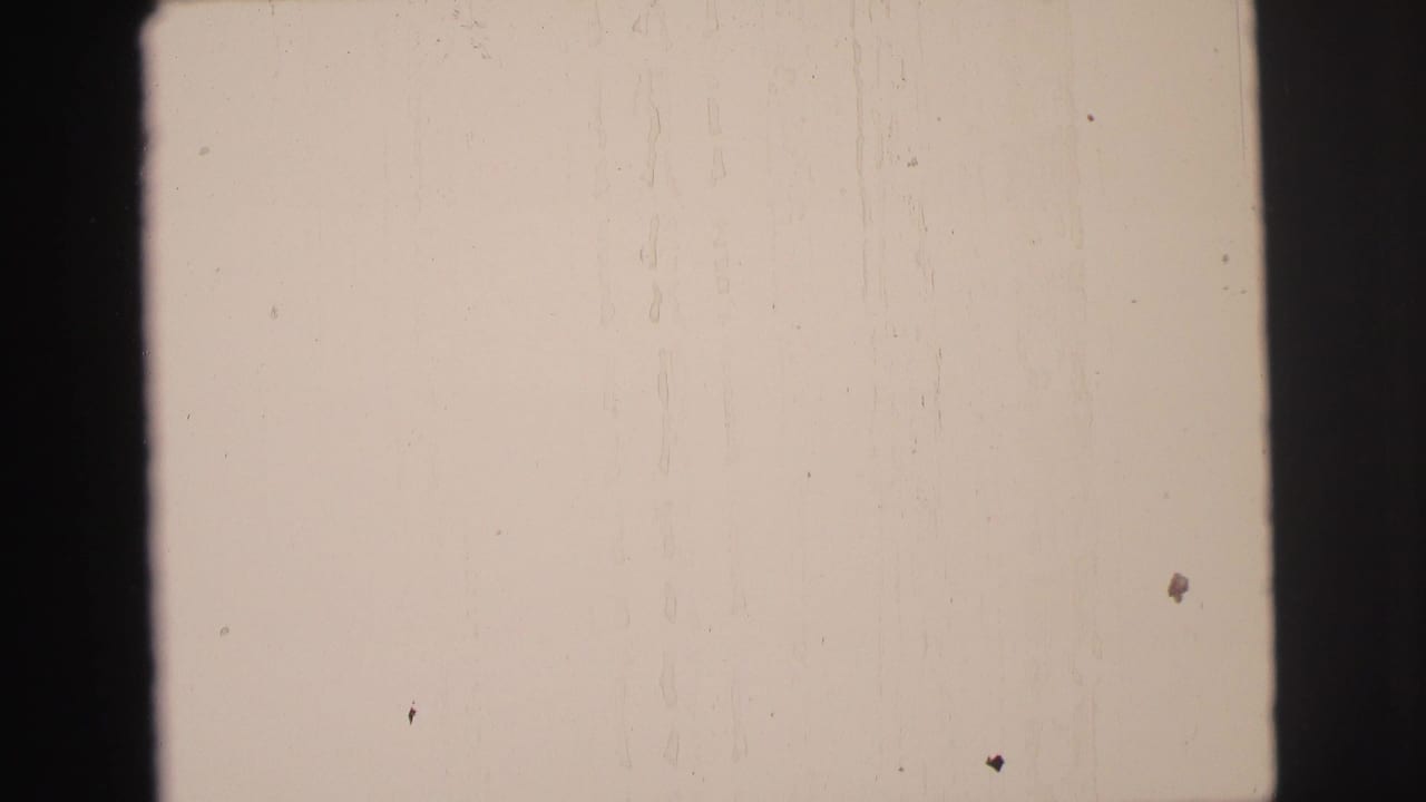 Mostly blank pale film frame bordered by dark window or frame edges.