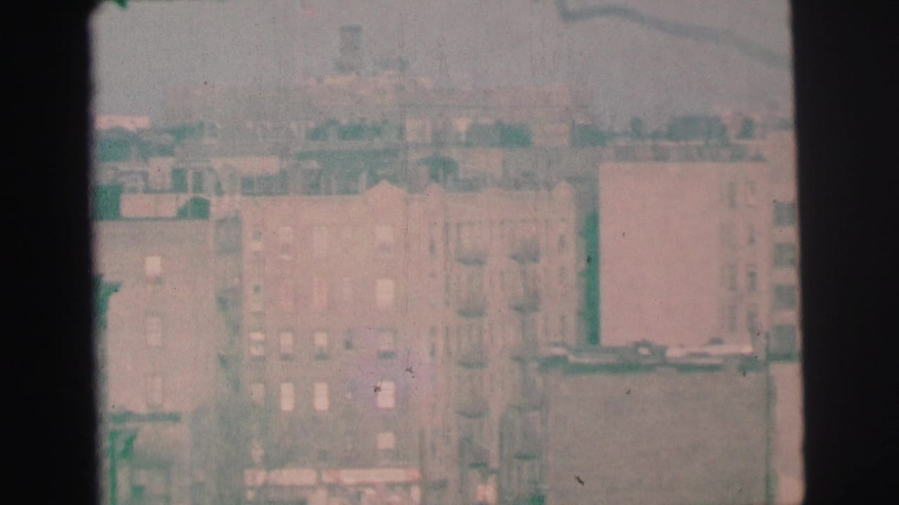 Hazy elevated view of brick buildings seen through dark window framing.