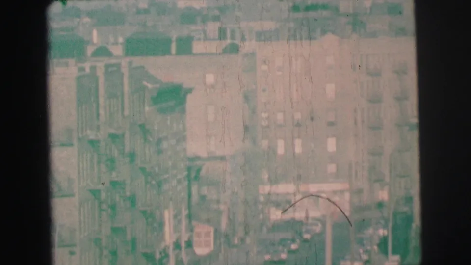 1973 Lynbrook elevated street view with apartment buildings, fire escapes, parked cars, and heavy 8mm haze and scratches.
