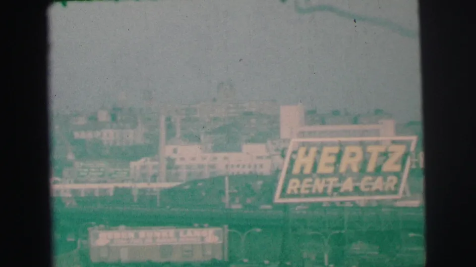 Green-tinted 1973 Lynbrook frame with Hertz Rent-A-Car signage, Weber Bunke Lanes, and low urban buildings.