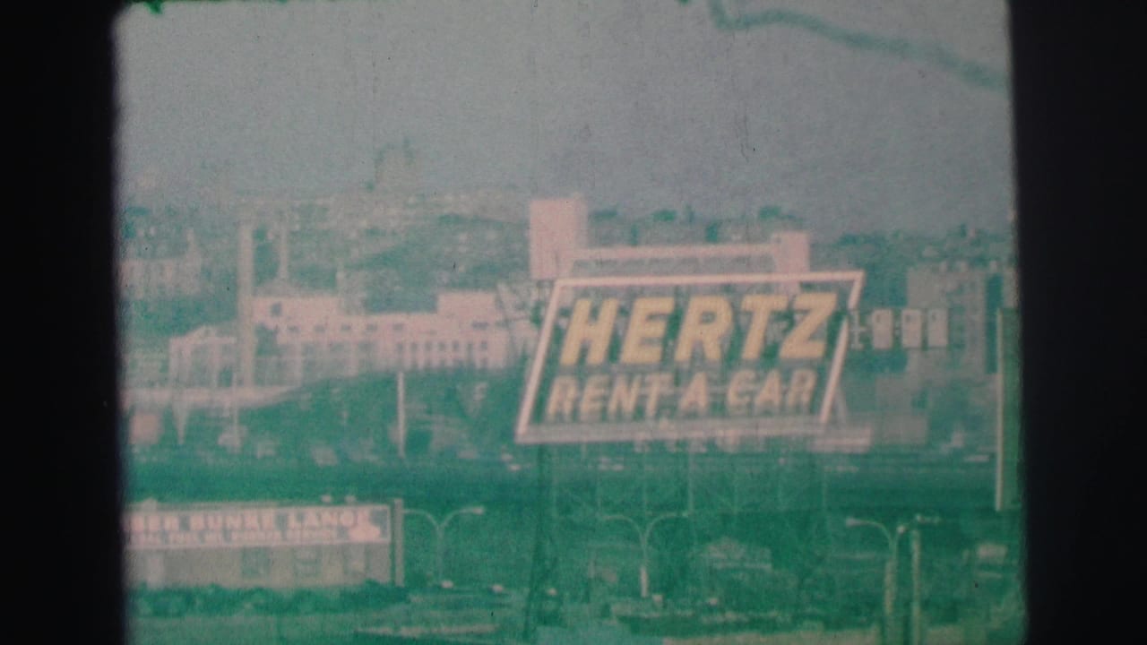 Hertz Rent-A-Car billboard seen through a soft green-tinted 8mm frame.