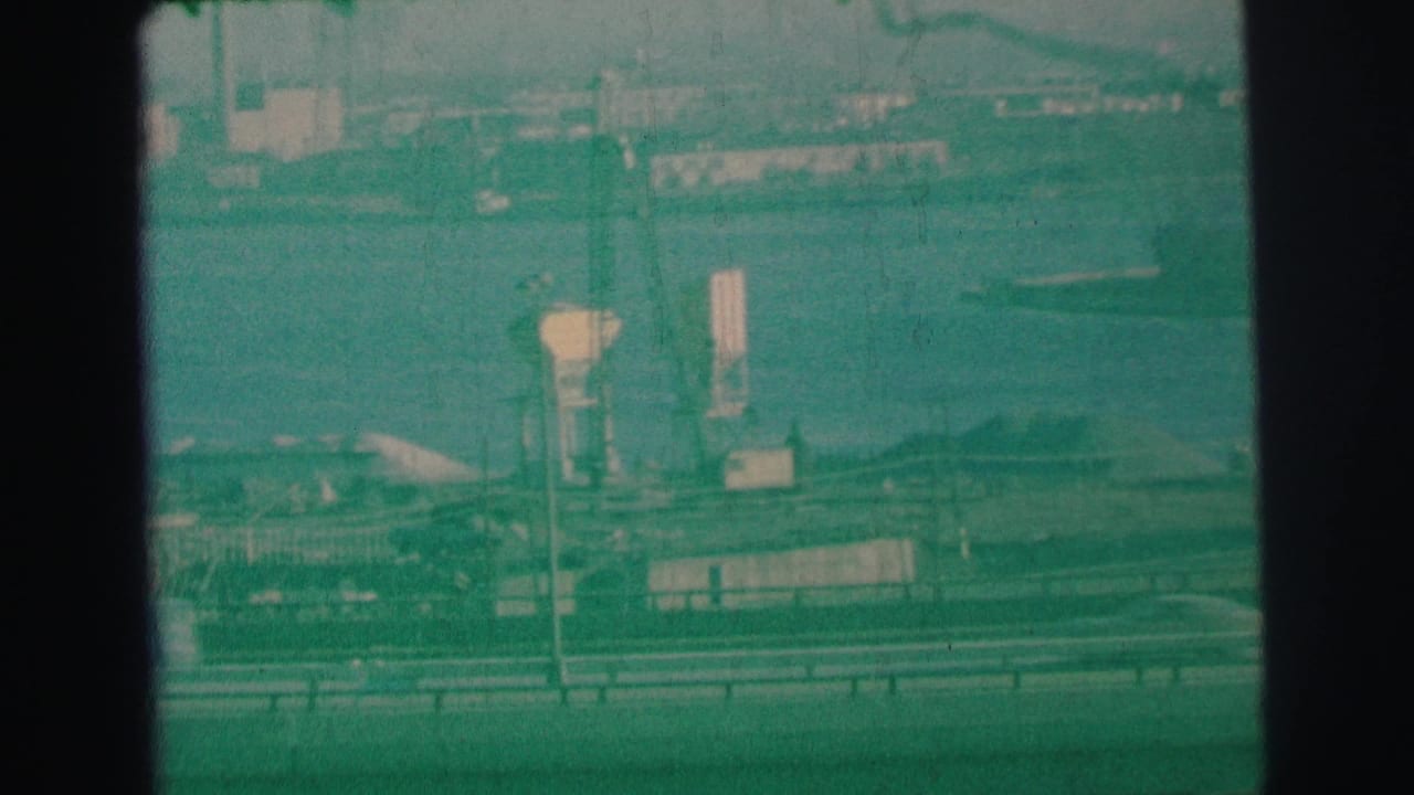 A freeway and bayfront industrial area appear through a green-tinted film frame.