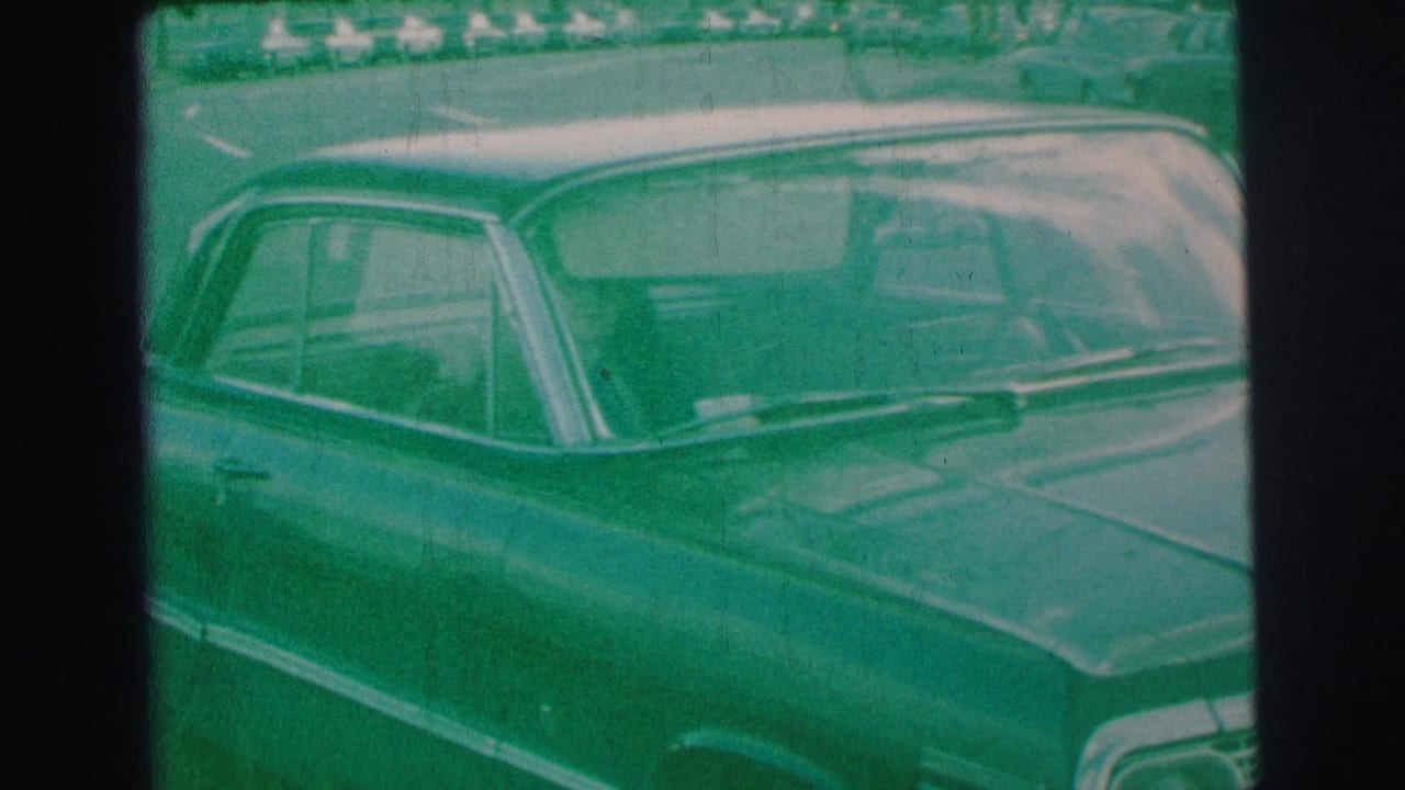 Parked dark sedan seen close up beside a curb, tinted green by the film scan.