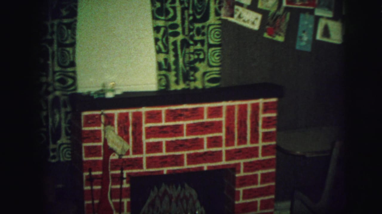 Red brick-patterned fake fireplace with patterned curtains and postcards above it.