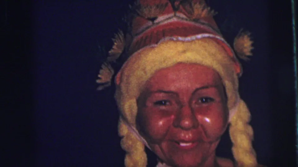Close-up of a smiling costumed woman with a yellow braided hat, filmed in grainy 8mm color in Lynbrook, New York, 1973.