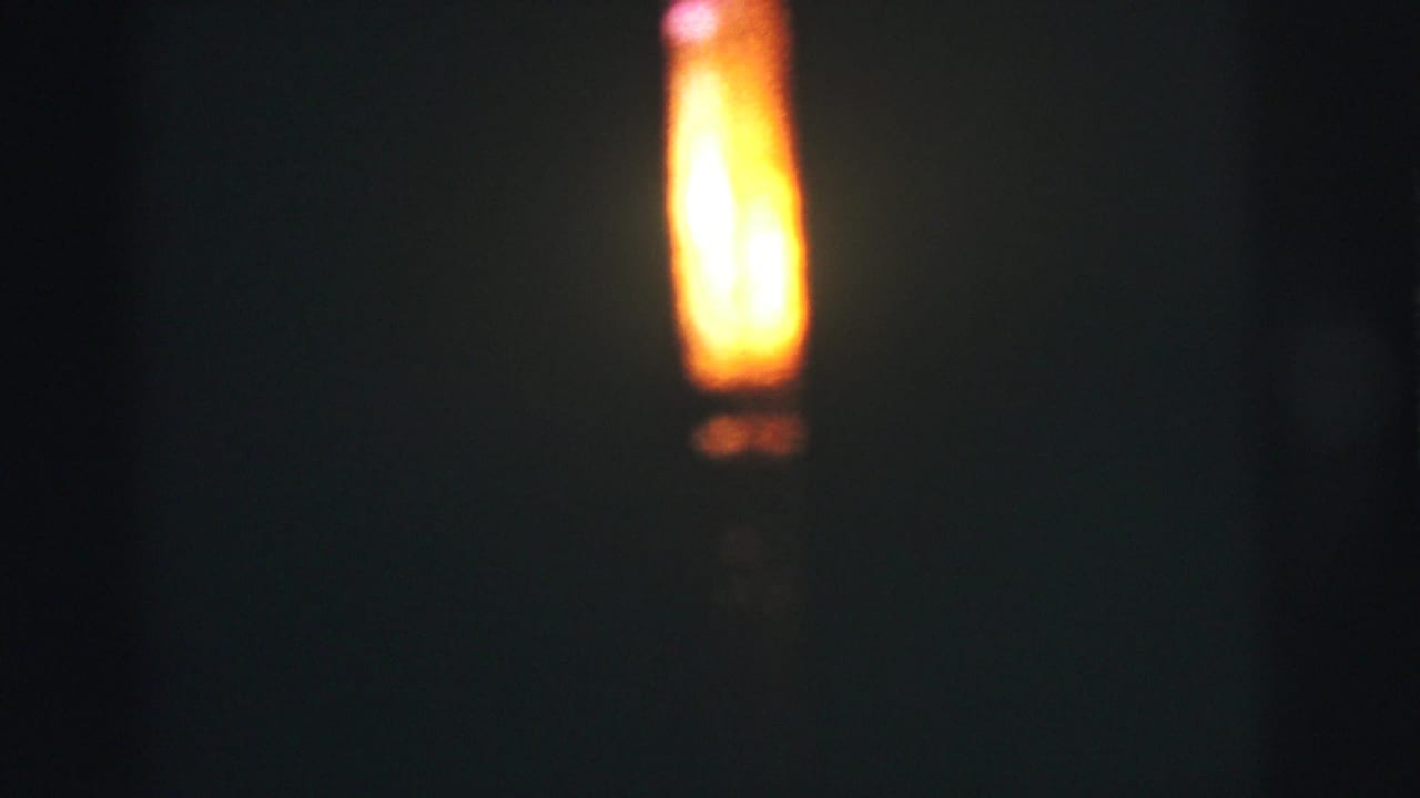 Bright vertical flame glowing against a nearly black background.