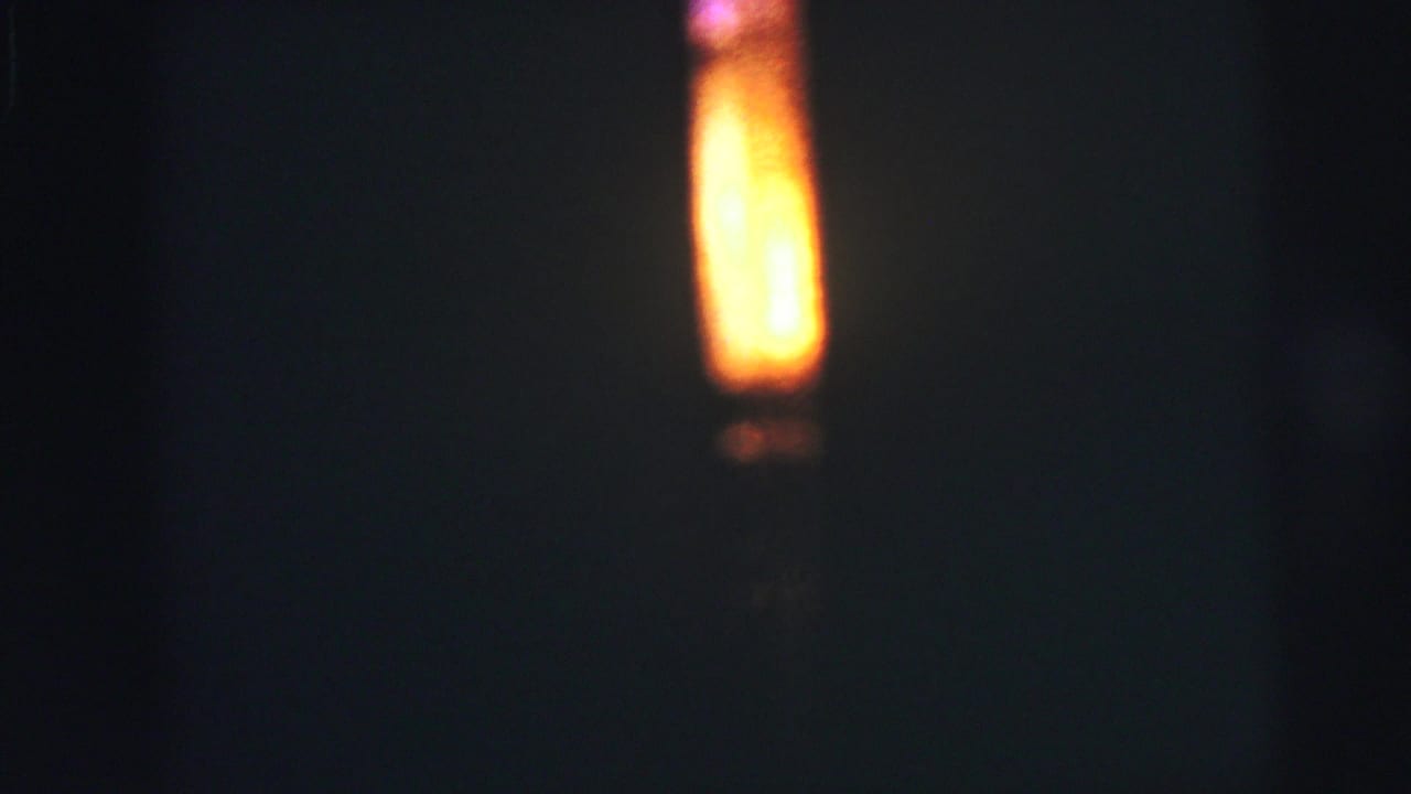A bright yellow-orange vertical glow appears against a dark, soft-focused background in 1973 Lynbrook 8mm home-movie footage.