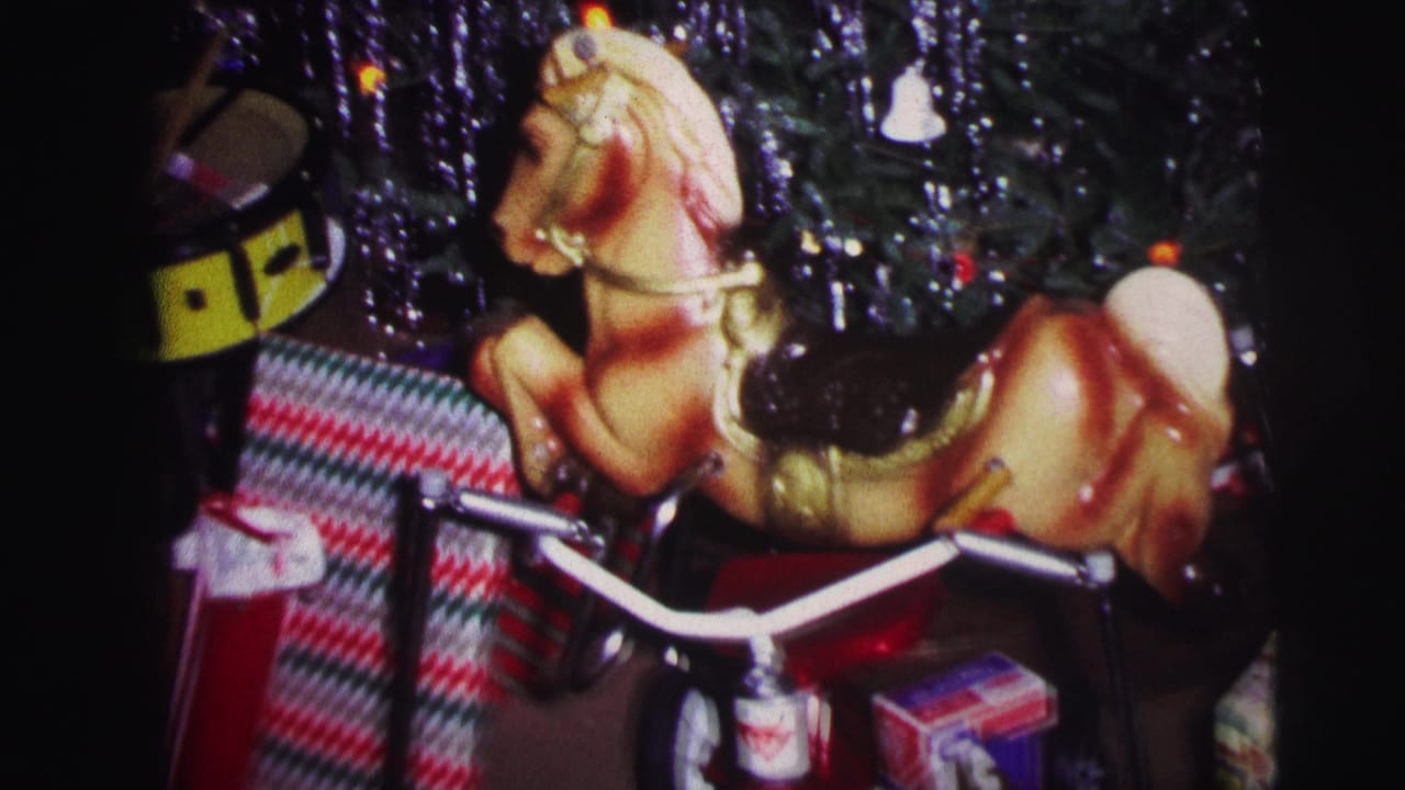 Toy rocking horse near wrapped presents and a yellow drum beside a decorated Christmas tree.