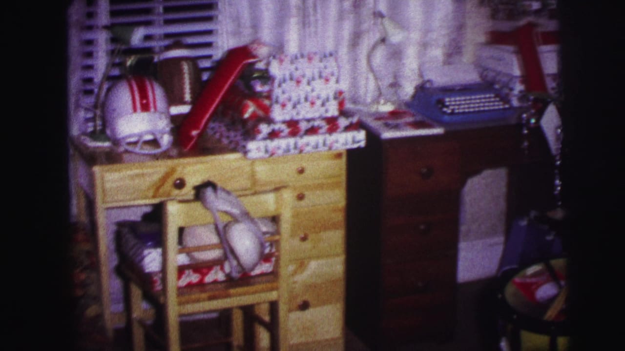 Desk with chair, wrapped presents, football helmet, blue typewriter, toy drum, and basketball.