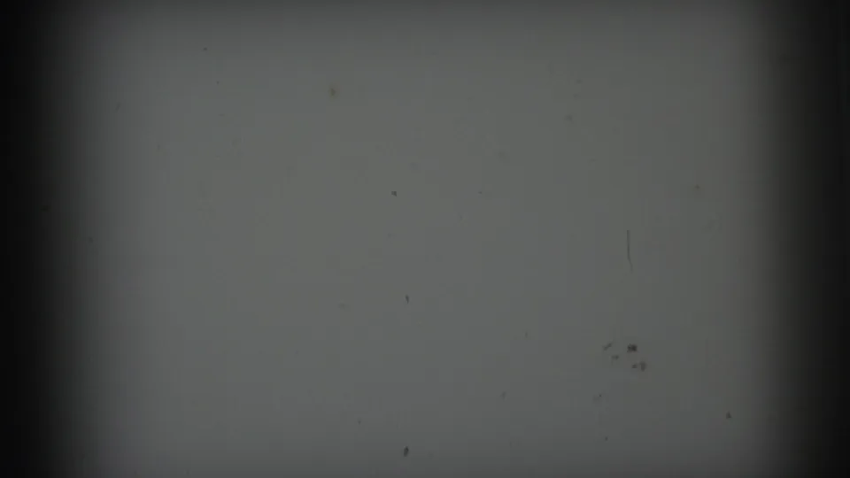1973 Lynbrook 8mm startup frame showing gray exposure, heavy vignette, dust and a faint scratch-like vertical mark.