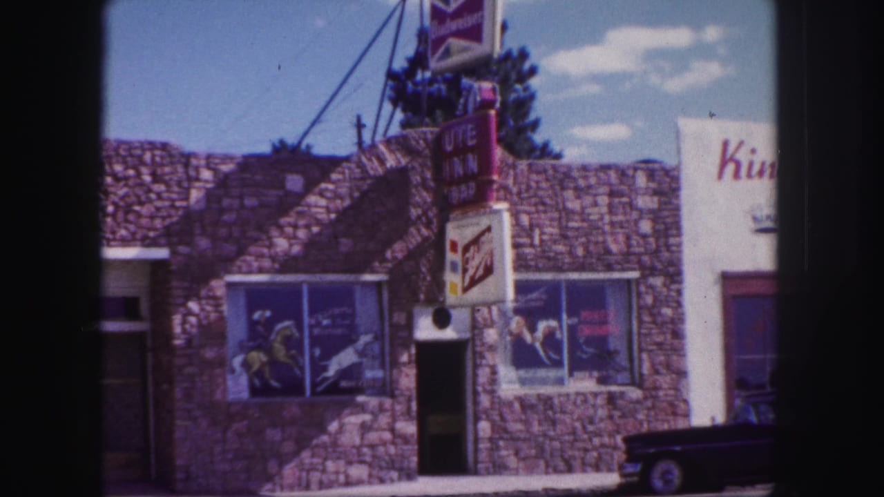 Storefront windows, vertical sign, beer ads, stone wall, and partial King's sign beside the building.