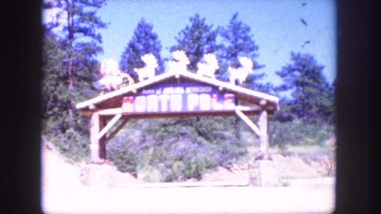 Wooden North Pole attraction arch appears beside trees in Colorado Springs-area 1958 home-movie footage.