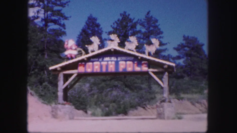 Closer 1958 view of a Colorado Springs-area North Pole sign with painted lettering and holiday figures above the arch.
