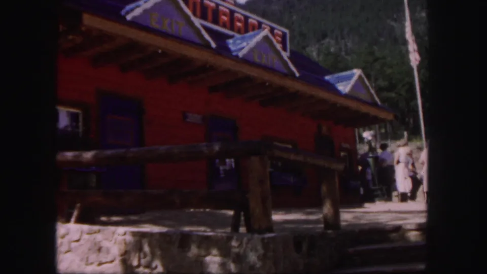 1958 Colorado Springs footage cuts to a red log-style exit building, with several visitors visible near the entrance area.